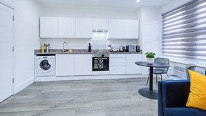 Eine moderne Küche mit weißen Schränken, einer eingebauten Waschmaschine und einem Essbereich mit Tisch und Stühlen.