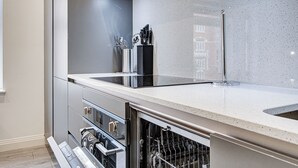 A modern kitchen with a dishwasher, built-in oven, and stainless steel appliances.