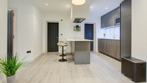 Een moderne keuken met een centraal eiland, donkere kastjes en een roestvrijstalen koelkast.