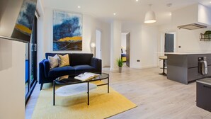 Een moderne woonkamer met een donkerblauwe bank, een salontafel en een groot abstract schilderij aan de muur.