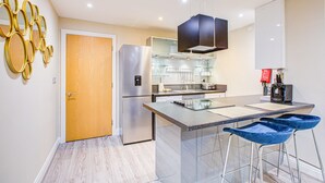 A modern kitchen with a central island, stainless steel appliances, and a bar area with stools.