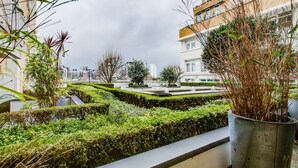 A landscaped garden area with hedges and plants, surrounded by residential buildings.