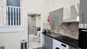 Une cuisine moderne équipée d’un lave-linge, d’un évier et d’une douche à parois de verre.