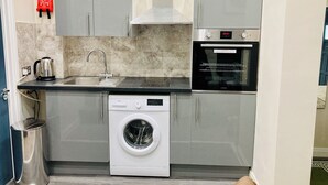 Une cuisine compacte équipée d’un lave-linge, d’une bouilloire et d’un four encastré.