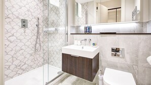 A modern bathroom with a glass-enclosed shower, a vanity with a dark wood cabinet, and a large mirror above the sink.