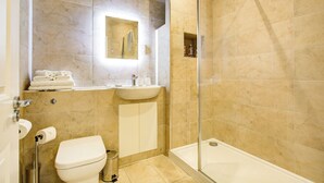 Un baño con inodoro, lavamanos, espejo y ducha.