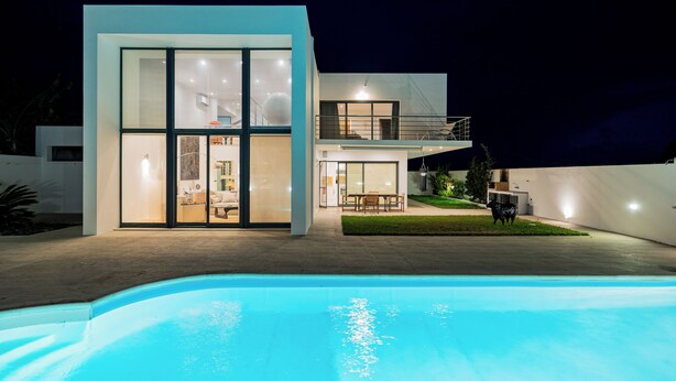 Una casa moderna de dos pisos con una piscina al frente.