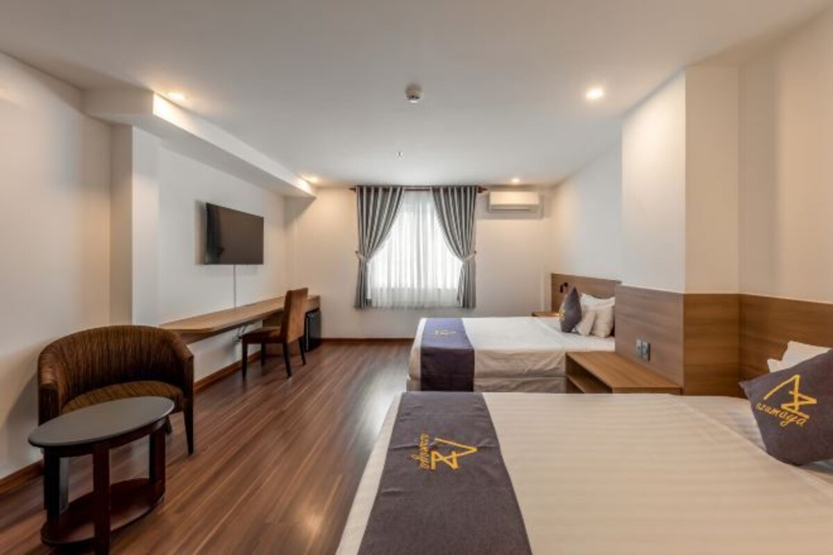A hotel room with a bed, a desk, a chair, and a television.