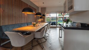 Un comedor moderno con una mesa de madera, sillas tapizadas en gris e iluminación colgante.