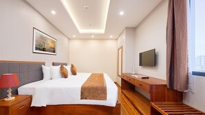 A hotel room with a bed, bedside table, TV, and a view of the city. - Mercury Apartment Danang (Da Nang)