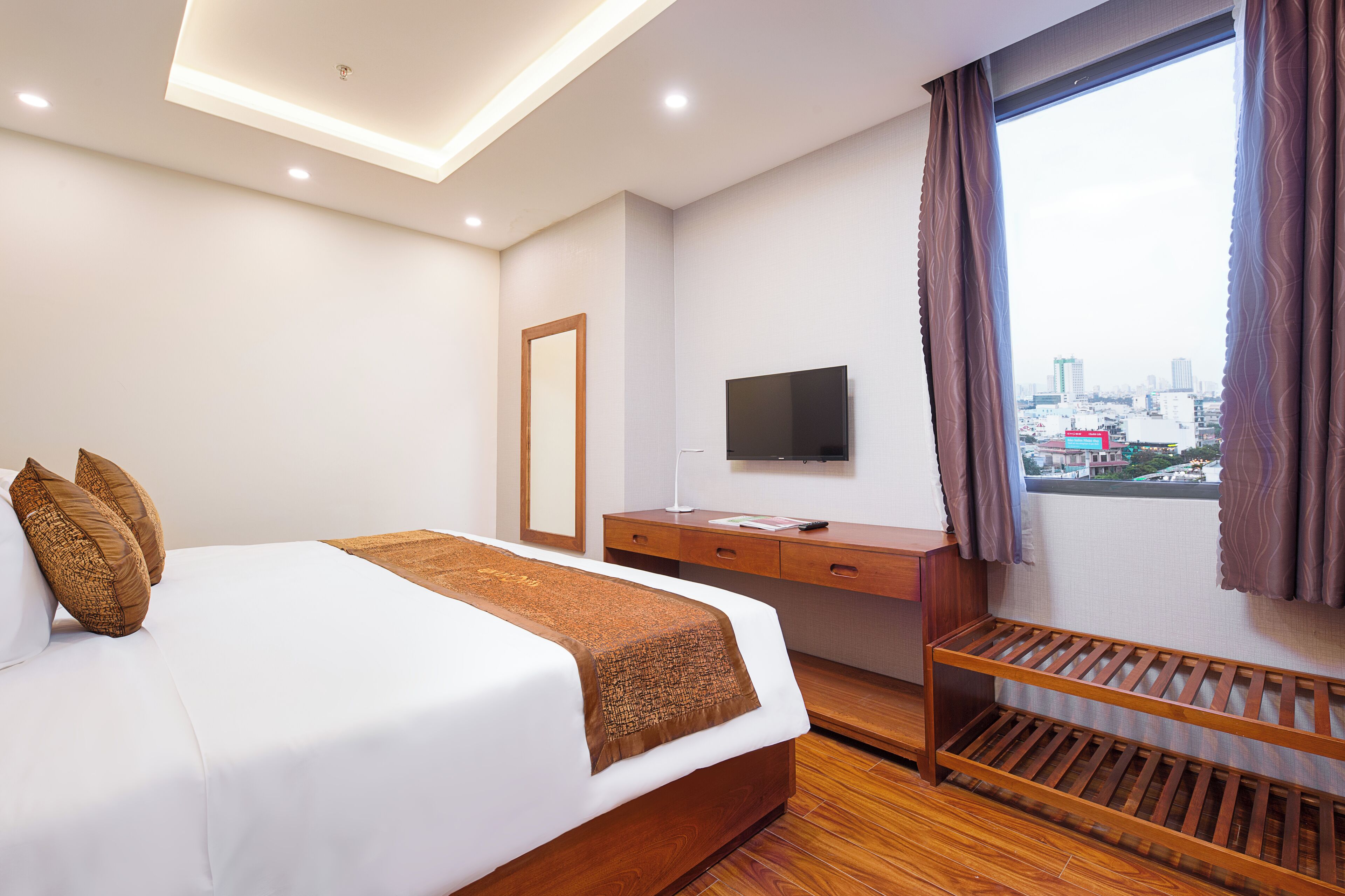 Habitación de hotel con cama, escritorio, televisor y ventana con vista a la ciudad.