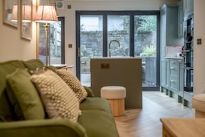 A modern kitchen with a built-in oven, a sink, and a window overlooking a garden.