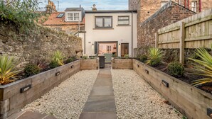 A courtyard with a pathway leading to a modern building with large windows and a door.