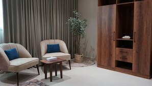 Una sala de estar moderna con dos sillones, una mesita, una planta en maceta y un mueble de madera.