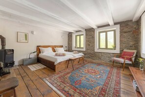 Un dormitorio con una cama de madera, una pared de piedra y un ventanal grande.