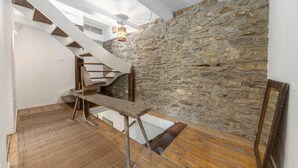 Un escalier avec une rampe en bois, un mur en pierre et un plancher en bois.