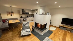 Una sala de estar moderna con chimenea, un comedor y una cocina al fondo.