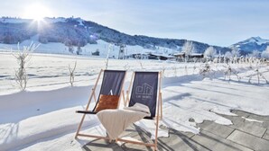 Un espacio al aire libre cubierto de nieve, con dos sillones de exterior y una terraza de madera.