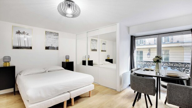 A modern bedroom with a bed, bedside tables, a dining table with chairs, and a large window. - Appartement in the heart of Paris ☆ Opera ☆ (Paris)