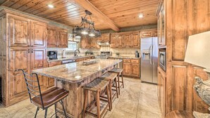A spacious kitchen with wooden cabinets, a large island with bar stools, and modern appliances. - Lakeside Haven with Sandy Beach, Sleeps 12, 3 Bath (Stigler)