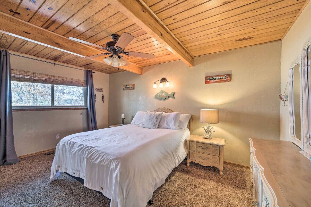 Ein Schlafzimmer mit Holzboden, einem Bett mit weißer Bettwäsche, einem Nachttisch mit Lampe und einer Kommode.