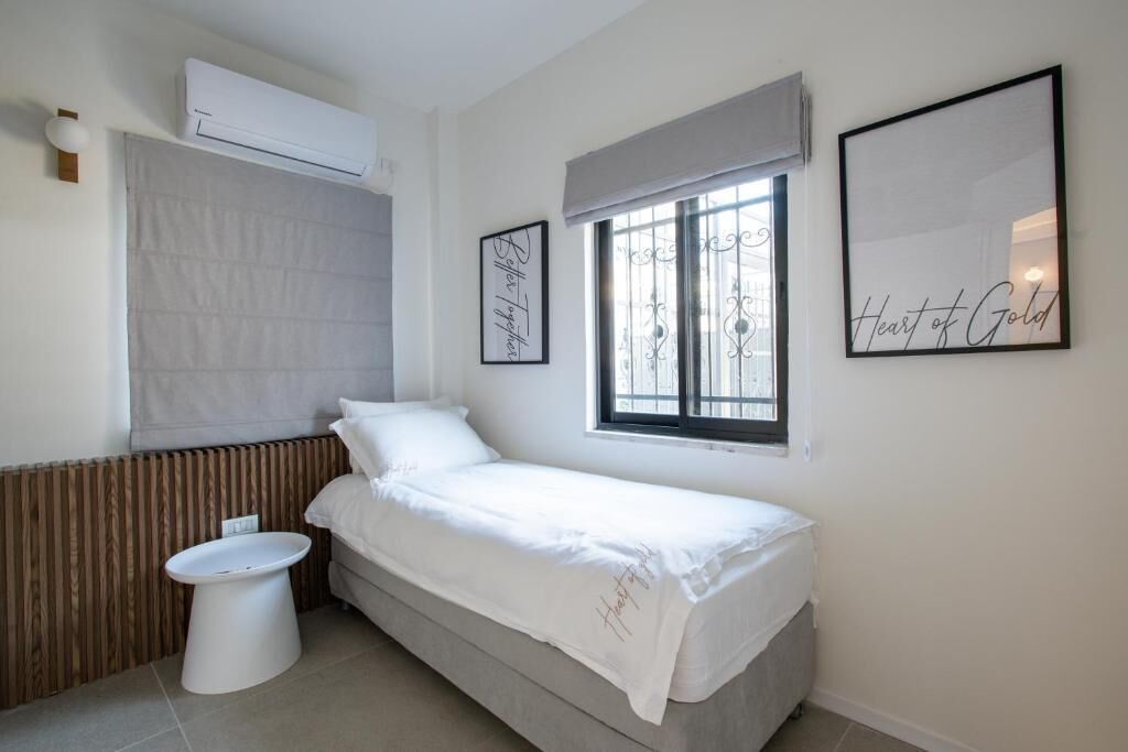 A small, clean room with a bed, a window, a toilet, and a radiator.