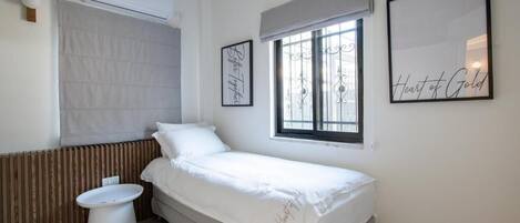 A small, clean room with a bed, a window, a toilet, and a radiator.