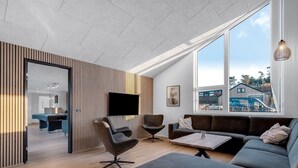 Una sala de estar moderna con mesa de billar, asientos cómodos y un gran ventanal con vistas al exterior.