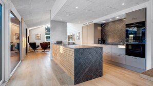 Una cocina moderna con una isla de mármol, armarios de madera y un ventanal grande.