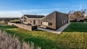 Una casa moderna con techo plano, ventanas amplias y un césped bien cuidado.