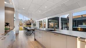Una cocina moderna con una encimera amplia, una zona de comedor con sillas y un ventanal con vistas al exterior.