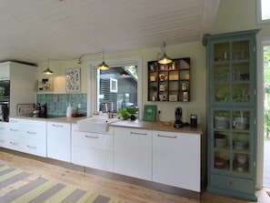 A kitchen with white cabinets, a sink, a coffee maker, and a cabinet with glass doors containing plates.