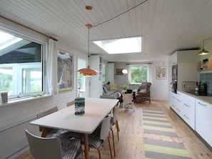 A modern kitchen with white cabinets, a dining area with a table and chairs, and a large window with curtains.