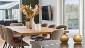 Un comedor moderno con una mesa de madera, sillas y un jarrón de flores.