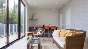 Una sala moderna con una mesa de centro de vidrio, sofá de mimbre y sillones naranjas.