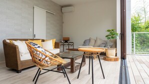 Una sala de estar moderna con sofá, una mesa de centro de vidrio y una silla de mimbre.