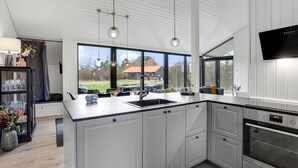 Una cocina moderna con una isla grande, armarios blancos y un horno empotrado.