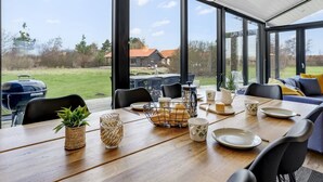 Un comedor moderno con una mesa de madera, sillas y vistas al exterior.