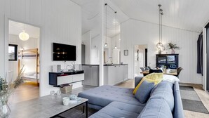 Una sala de estar moderna con un sofá gris, una mesa de centro y un televisor montado en la pared.