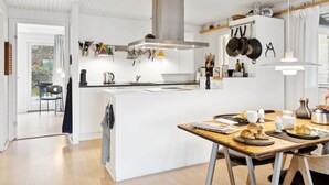 A modern kitchen with white cabinetry, a central island, and hanging pots. - "Henryette" - 1.5km from the sea by Interhome (Ebeltoft)