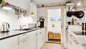 A modern kitchen with white cabinets, a black countertop, and stainless steel appliances. There is a window providing natural light and a view of the outdoors. - "Henryette" - 1.5km from the sea by Interhome (Ebeltoft)