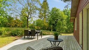 A wooden deck with a wicker chair, a small table, and a dining set. - "Henryette" - 1.5km from the sea by Interhome (Ebeltoft)