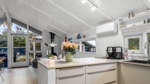 A modern kitchen with white cabinetry, a large island, and a view of the outdoors. - "Gonda" - 2km from the sea by Interhome (Saltum)