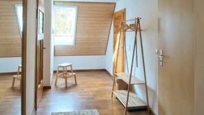 A room with a sloped ceiling, wooden flooring, a standing ladder, and a large window. - Sustainable, vegan-friendly accommodation at mining nature trail in Schneeberg (Schneeberg)