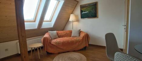 A cozy room with a wooden ceiling, a sofa, a lamp, and a painting on the wall.