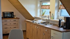 A compact kitchen with wooden cabinets, a small refrigerator, and a dining area with two chairs. - Sustainable, vegan-friendly accommodation at mining nature trail in Schneeberg (Schneeberg)