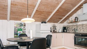 A modern kitchen with white cabinets, a black countertop, and a wooden ceiling. - 4 Person Holiday Home in Oksbol (Oksbol)