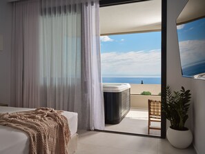 A bedroom with a bed, a large window, a hot tub, and a view of the sea. - The Sall Suites Complex B - Sea Views (Zakynthos)