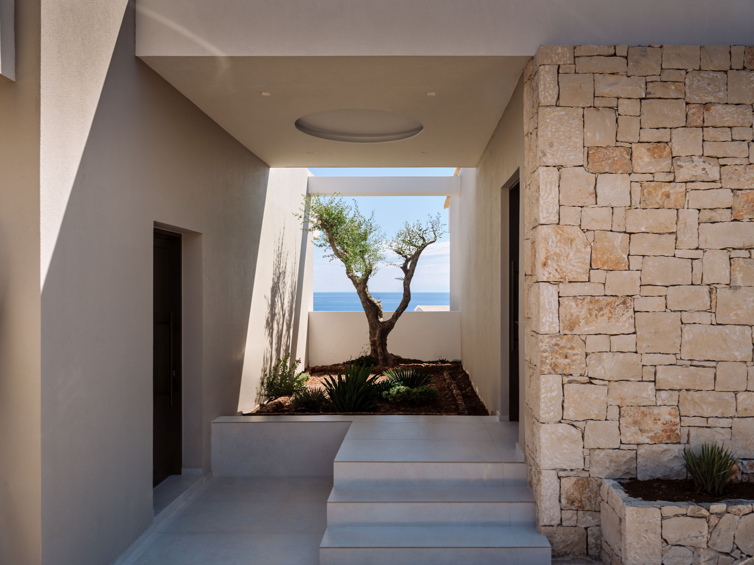 Un interior moderno con una escalera que conduce a un balcón con vistas al mar.