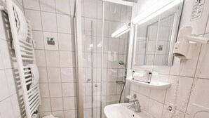 Ein modernes Badezimmer mit einer Duschkabine aus Glas, einem weißen Waschbecken und einer Toilette.